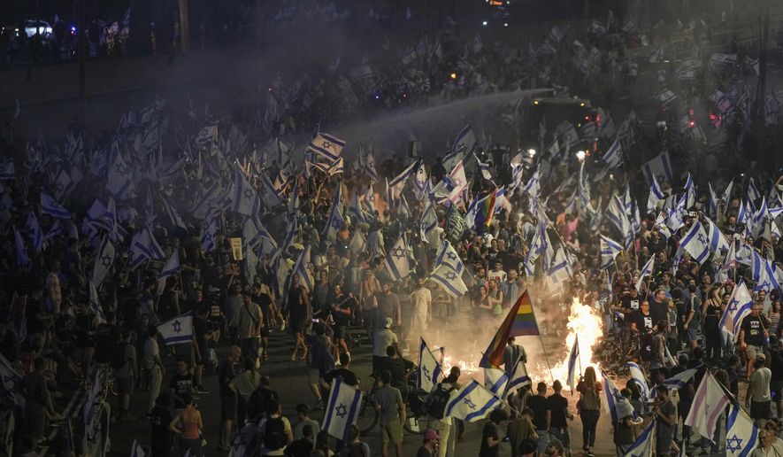 Israeli police use a water cannon to disperse demonstrators blocking the freeway during protest against plans by Prime Minister Benjamin Netanyahu's government to overhaul the judicial system in Tel Aviv, Israel, Wednesday, July 5, 2023. Protesters took to the streets in support of Tel Aviv's police chief, who announced his resignation on Wednesday. (AP Photo/Oded Balilty)