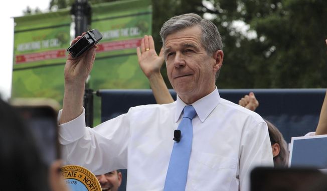 North Carolina Democratic Gov. Roy Cooper affixes his veto stamp to a bill banning nearly all abortions after 12 weeks of pregnancy at a public rally, May 13, 2023, in Raleigh, N.C. On Wednesday, July 5, Cooper vetoed a trio of bills aimed at LGBTQ+ youth that would ban gender-affirming health care for minors, restrict transgender participation in school sports and limit classroom instruction about gender identity and sexuality. (AP Photo/Hannah Schoenbaum, File)