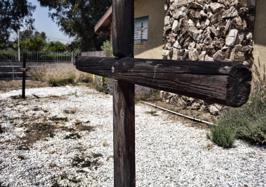 Burned crosses stand outside the Sylmar Christian Fellowship Church, Thursday, July 6, 2023, in the Sylmar section of Los Angeles. Three wooden crosses outside the small Los Angeles church were found burned early Thursday and authorities say the fire is being investigated as a possible hate crime. (AP Photo/Richard Vogel)