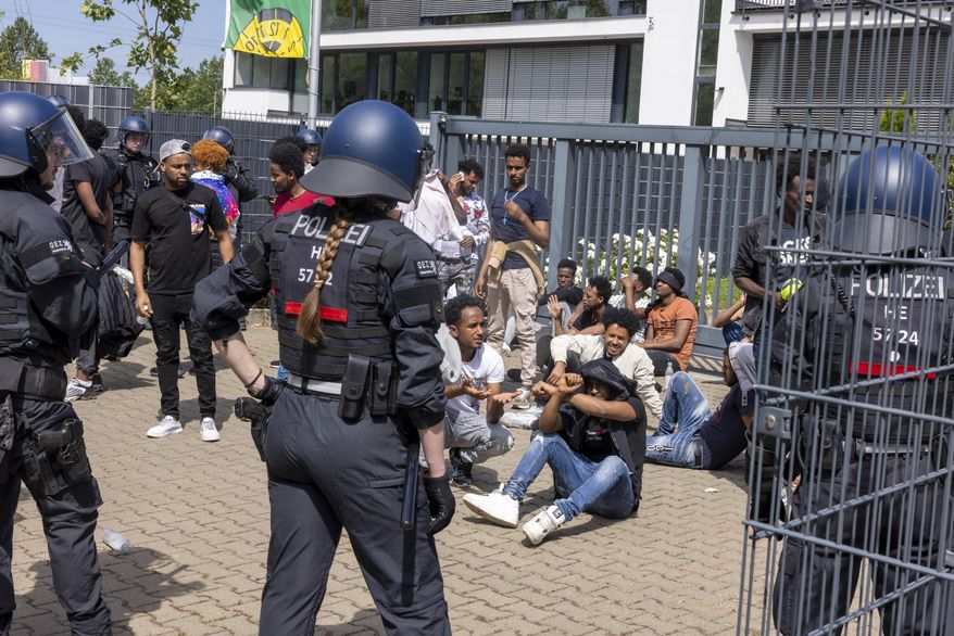 Police officers surrounded a group of people before the start of the Eritrea Festival in Giessen, Germany, Saturday, July 8, 2023. German police say several officers were injured and dozens of people were detained Saturday during unrest at an Eritrean cultural event in the western city of Giessen. Authorities had tried to ban the festival after similar unrest occurred there last year, but a court overturned the order. (Helmut Fricke/dpa via AP)