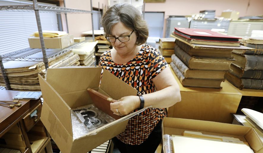 New Bedford Public Library Director Olivia Melo, pulls the 100 year overdue book from the box shipped to New Bedford, Mass., from West Virginia University Library on Friday, July 7, 2023. "An Elementary Treatise on Electricity" by James Clerk Maxwell was returned to the West Virginia University library one hundred years after it was taken out of the New Bedford Public library in 1903. (Peter Pereira/The Standard-Times via AP)