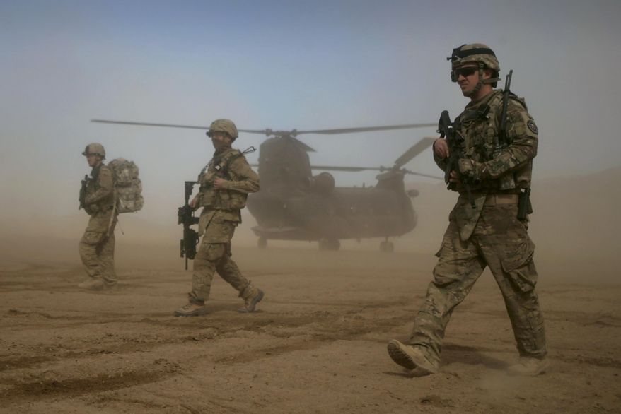 U.S. soldiers, part of the NATO- led International Security Assistance Force (ISAF), walk as a U.S. Chinook helicopter is seen in the background in Shindand, Herat, west of Kabul, Afghanistan, on Jan. 28, 2012. On the ground, NATO has helped to keep peace in the Balkans and combat the Taliban-led insurgency in war-torn Afghanistan, the alliance's biggest ever operation, launched after the United States triggered its "all for one and one for all" common defense clause in the wake of the Sept. 11, 2001 attacks. (AP Photo/Hoshang Hashimi) **FILE**