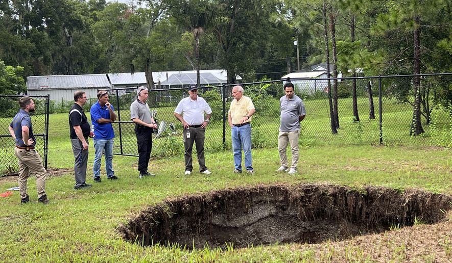 This photo provided by Hillsborough County, Fla., shows a sinkhole that in 2013 fatally swallowed a man sleeping in his own house. The sinkhole has reopened for a third time, this time behind chain-link fencing and doing no harm to people or property. Hillsborough County officials said the sinkhole located in the Tampa suburb of Seffner, Fla., appeared again on Monday, July 10, 2023, which they said is not unusual for such underground formations especially in central Florida with its porous limestone base. (Todd Pratt/Hillsborough County via AP)