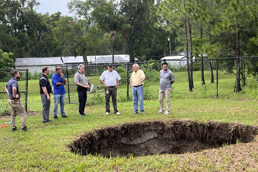 This photo provided by Hillsborough County, Fla., shows a sinkhole that in 2013 fatally swallowed a man sleeping in his own house. The sinkhole has reopened for a third time, this time behind chain-link fencing and doing no harm to people or property. Hillsborough County officials said the sinkhole located in the Tampa suburb of Seffner, Fla., appeared again on Monday, July 10, 2023, which they said is not unusual for such underground formations especially in central Florida with its porous limestone base. (Todd Pratt/Hillsborough County via AP)