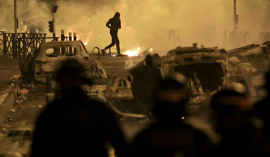 A demonstrator runs on the third night of protests sparked by the fatal police shooting of a 17-year-old driver in the Paris suburb of Nanterre, France, Friday, June 30, 2023. Widespread riots in France sparked by the police killing of a teenager with North African roots have revealed the depth of discontent roiling poor neighborhoods — and given a new platform to the increasingly emboldened far right. (AP Photo/Aurelien Morissard, File)