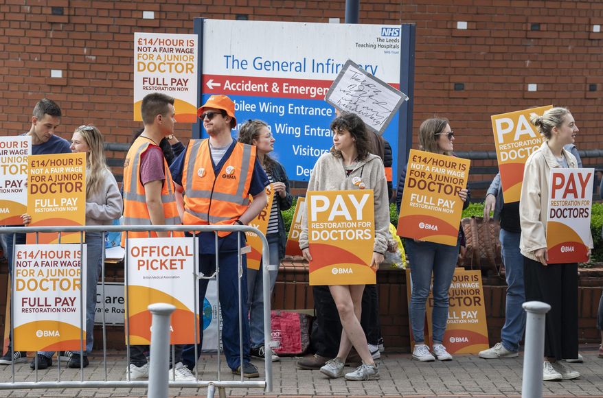 Junior doctor and members of the British Medical Association (BMA) stand on the picket line outside Leeds General Infirmary at the start a five-day strike amid the continuing dispute over pay, the longest walkout of its kind in the history of the NHS, in Leeds, England, Thursday July 13, 2023. (Danny Lawson/PA via AP)