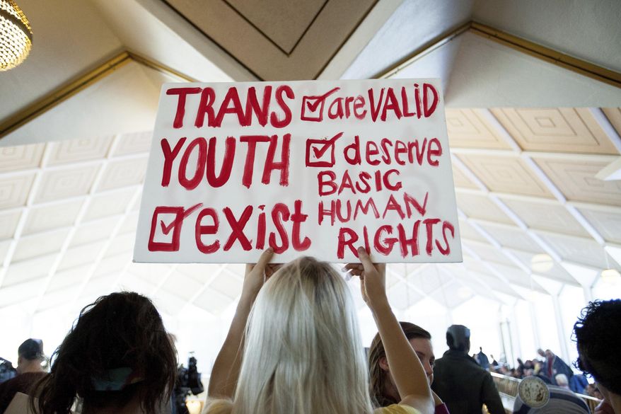 Hunter Schafer, of Raleigh, holds a sign supporting transgender youth during a special session of the North Carolina General Assembly in Raleigh, N.C., Dec. 21, 2016. While Republican lawmakers in North Carolina gear up to override vetoes of bills restricting rights of transgender people, courts across the country have been taking opposing stances on similar laws. If the override efforts are successful, the state will join most other GOP-controlled ones in limiting gender-affirming care such as puberty blockers and hormone treatments for minors. (AP Photo/Ben McKeown, File)