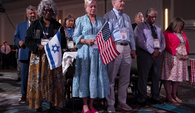 Holding U.S. and Israeli flags, a crowd of largely Evangelical Christians pray during the Christians United For Israel (CUFI) &quot;Night to Honor Israel&quot; during the CUFI Summit 2023, Monday, July 17, 2023, in Arlington, Va., at the Crystal Gateway Marriott. (AP Photo/Jacquelyn Martin)