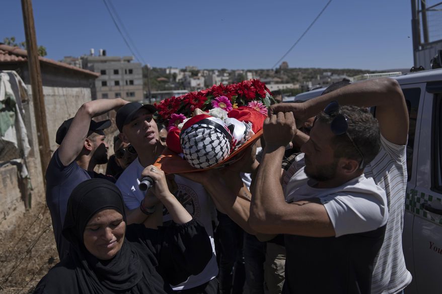 Maisa al-Bayed, left, carries the body of her son Muhammad al-Bayed, 17, during his funeral in the West Bank village of Jifna, north of Ramallah, Saturday, July 22, 2023. Israeli forces shot and killed al-Bayed in the occupied West Bank Friday, Palestinian health officials said. The Israeli army said that a member of the paramilitary border police unit opened fire after masked suspects threw stones and rocks at Israeli forces. It confirmed that a person was hit by gunfire, but gave no further details. (AP Photo/Nasser Nasser)