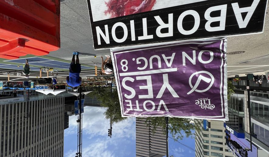 A sign asking Ohioans to vote in support of Issue 1 sits above another sign advocating against abortion rights at an event hosted by Created Equal on Thursday, July 20, 2023, in Cincinnati, Ohio. The fraught politics of abortion have helped turn an August ballot question in Ohio that would make it harder to change the state constitution into a cauldron of misinformation, fear-mongering and vitriol. (AP Photo/Patrick Orsagos)