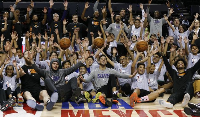 Phoenix Suns&#x27; players and coaches pose with young athletes following an NBA Cares basketball clinic, a day before their regular-season NBA game against the San Antonio Spurs in Mexico City, Friday, Dec. 13, 2019. The NBA has announced the Atlanta Hawks and Orlando Magic will play a regular-season game in Mexico City on Nov. 9. It will be the 32nd NBA game in Mexico since 1992. (AP Photo/Rebecca Blackwell, File)