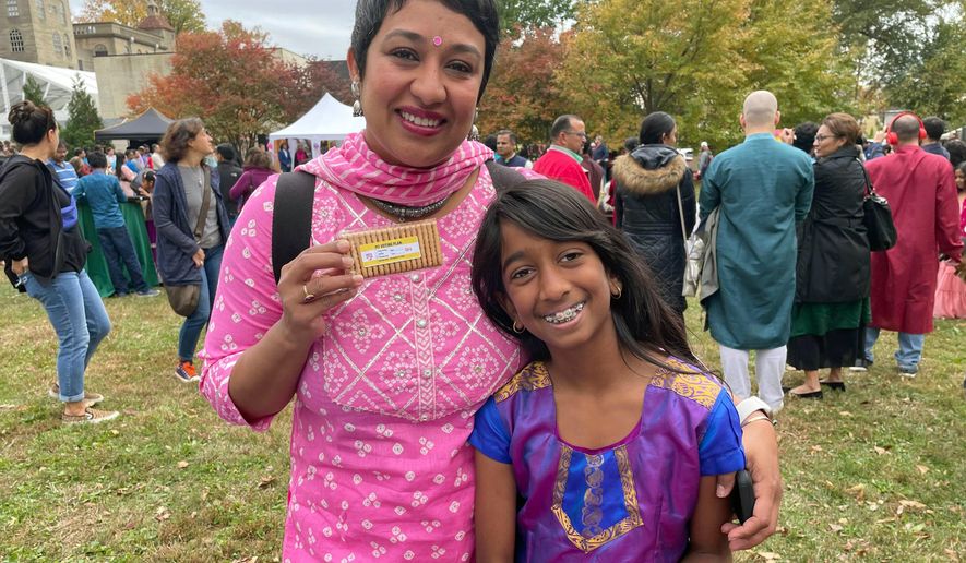 In this image provided by Sarah Shah, the advocacy group Indian American Impact, which runs the fact-checking site Desifacts.org, passes out Parle-G cookies with voting plan stickers at a Diwali even in Doylestown, Pa., on Oct. 23, 2022. Community organizations are gearing up for what they expect will be a worsening onslaught of disinformation targeting voters of color as the 2024 election approaches. (Sarah Shah via AP)