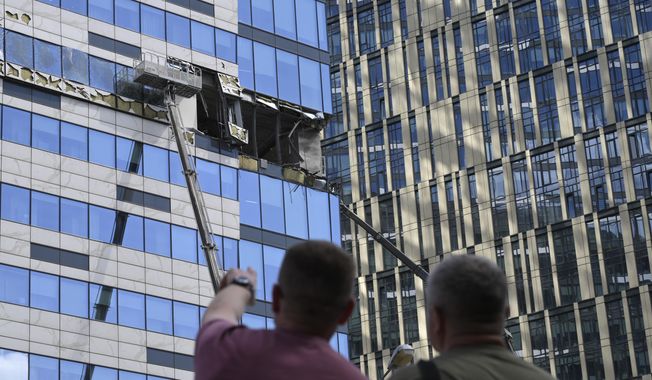 People watch as crane workers dismantle debris from a damaged skyscraper in the &quot;Moscow City&quot; business district after a reported drone attack in Moscow, Russia, Sunday, July 30, 2023. (AP Photo)