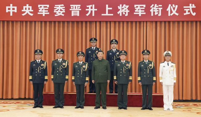 In this photo released by Xinhua News Agency, Chinese President Xi Jinping, also chairman of the Central Military Commission (CMC), center, poses for photos with the commander of the rocket force Wang Houbin, top left, and its political commissar Xu Xisheng, top right, after promoting them to the rank of general in Beijing on Monday, July 31, 2023. Banner above reads &quot;Central Military Commission Promotion to General Ceremony&quot; (Li Gang/Xinhua via AP)
