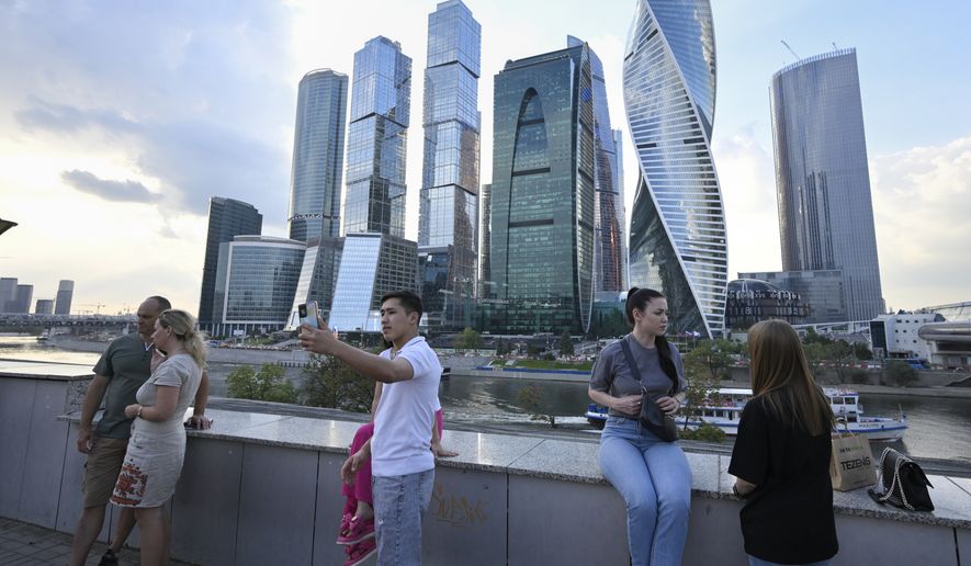 People stroll at embankment of the Moscow River in Moscow, Russia, Tuesday, Aug. 1, 2023, with the "Moscow City" business district in the background. The glittering towers of the Moscow City business district were once symbols of the Russian capital's economic boom in the early 2000s. Now they are a sign of its vulnerability, following a series of drone attacks that rattled some Muscovites shaken and brought the war in Ukraine home to the seat of Russian power. (AP Photo/Dmitry Serebryakov)