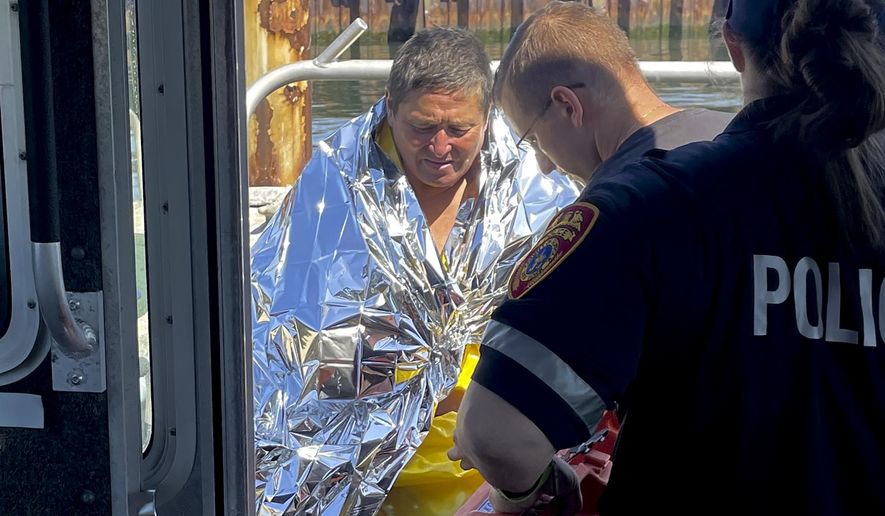 This image provided by Suffolk County Police shows Dan Ho, left, being treated by medics after having been rescued after treading water for five hours in the Atlantic Ocean off the coast of Long Island, Monday, July 31, 2023, in Babylon, N.Y. Suffolk County Police say that the 63-year-old went swimming at a beach in Babylon at around 5 a.m. Monday and was pulled out to open water by the current. (Courtesy of the Suffolk County Police via AP)