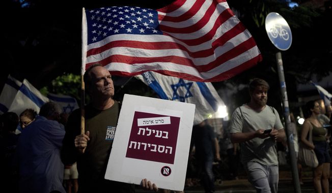 A man carries the U.S. flag with a placard reading, &quot;horror movie for the sake of reasonableness,&quot; as Israelis march in support of the judicial system during a protest against the plans by Prime Minister Benjamin Netanyahu&#x27;s government to overhaul it, in Tel Aviv, Israel, Wednesday, Aug. 2, 2023. (AP Photo/Maya Alleruzzo)