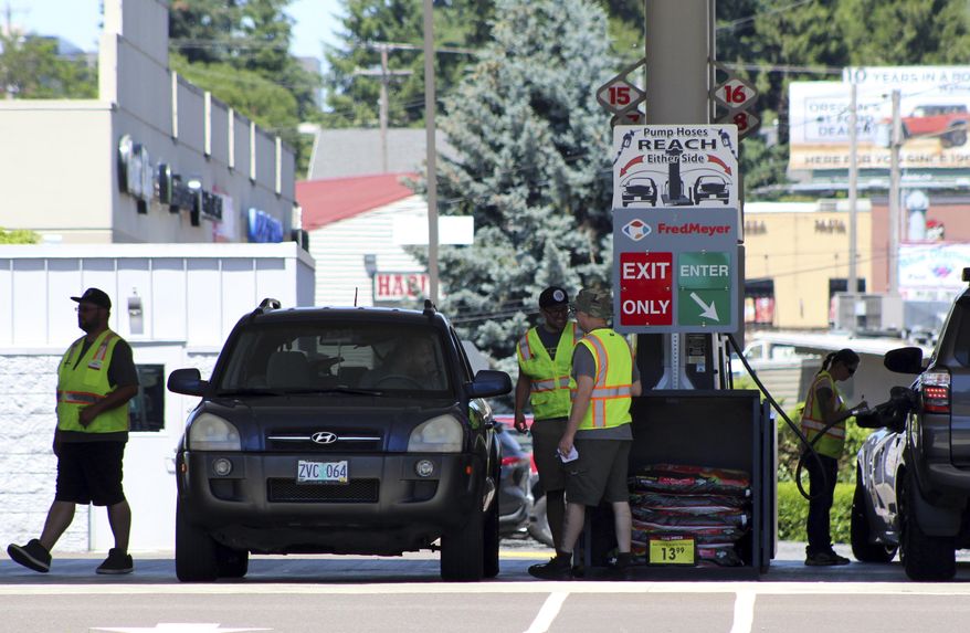 Attendants in vests service cars at a gas station in Salem, Oregon, on Thursday, June 22, 2023. In 1951, Oregon banned self-serve pumps at filling stations, being the only U.S. state besides New Jersey to do so. But now, the Oregon Legislature has decided that people across the state should be able to choose between having an attendant pump the gas or do it themselves. Gov. Tina Kotek signed the bill into law on Friday, Aug. 4, 2023, taking effect immediately. (AP Photo/Andrew Selsky)