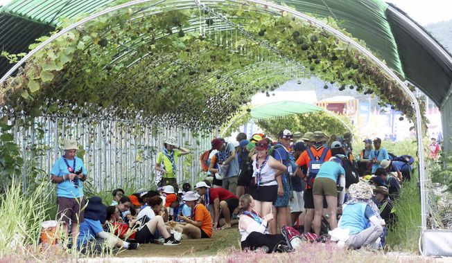 Attendees of the World Scout Jamboree beat the heat under a vine tunnel at a campsite in Buan, South Korea, Friday, Aug. 4, 2023. More than 100 people were treated for heat-related illnesses at the World Scout Jamboree being held in South Korea, which is having one of its hottest summers in years. (Choe Young-soo/Yonhap via AP)