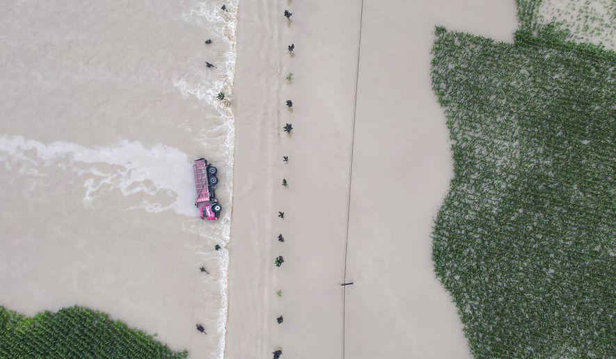 In this aerial photo released by Xinhua News Agency, a truck turned on its side is seen as flood waters flowing across roads and fields in Kaiyuan Town of Shulan in northeastern China's Jilin Province on Friday, Aug. 4, 2023. Northeastern China continued to be pelted by rain on Saturday, as authorities reported more deaths and missing people and evacuated thousands in the wake of Typhoon Doksuri. (Yan Linyun/Xinhua via AP)