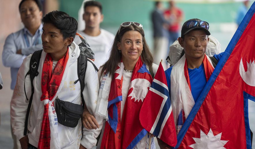 Norwegian woman mountain climber Kristin Harila, center and her Nepali Sherpa guide Tenjen Sherpa, right, who on Thursday set a new record by scaling the world's 14 highest peaks in 92 days arrive at the airport in Kathmandu, Nepal, Saturday, Aug.5, 2023. (AP Photo/Niranjan Shreshta)