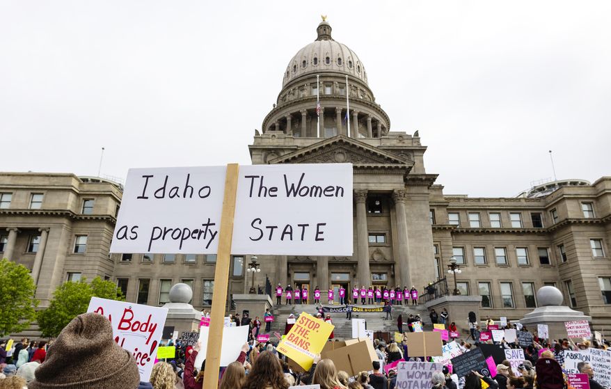 An attendee at Planned Parenthood's Bans Off Our Bodies rally for abortion rights holds a sign reading outside of the Idaho Statehouse in downtown Boise, Idaho, on May 14, 2022. Six university professors and two teachers’ unions are suing Idaho over a law that they say violates their First Amendment rights by criminalizing teaching and classroom discussion about pro-abortion viewpoints. (Sarah A. Miller/Idaho Statesman via AP, File)