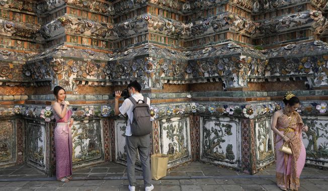 A Chinese tourist in traditional Thai dress poses for a photograp at Wat Arun or the &quot;Temple of Dawn&quot; in Bangkok, Thailand, on Jan. 12, 2023. On Thursday, Aug. 10, 2023, China increased the number of countries that its big-spending tourists can visit by more than 70 following the lifting of its last COVID-19 travel restrictions. (AP Photo/Sakchai Lalit, File)