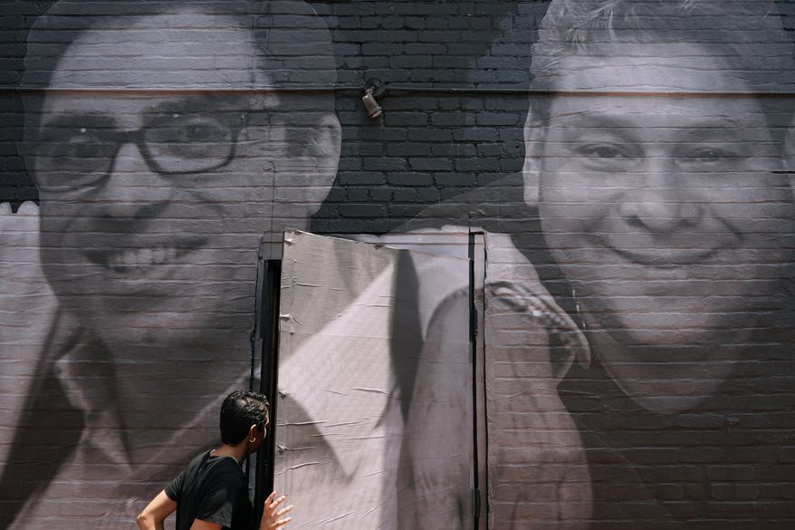 A woman steps through a door that is covered by a mural depicting American hostages and wrongful detainees who are being held abroad, Wednesday, July 20, 2022, in the Georgetown neighborhood of Washington. At left is Siamak Namazi, who has been in captivity in Iran since 2015. At right is Jose Angel Pereira, who has been imprisoned in Venezuela since 2017. Iran has transferred five Iranian-Americans from prison, identifying three of the prisoners as Siamak Namazi, Emad Shargi, and Morad Tahbaz, to house arrest. The move comes after Tehran has spent months suggesting a prisoner swap with Washington. (AP Photo/Patrick Semansky, File)