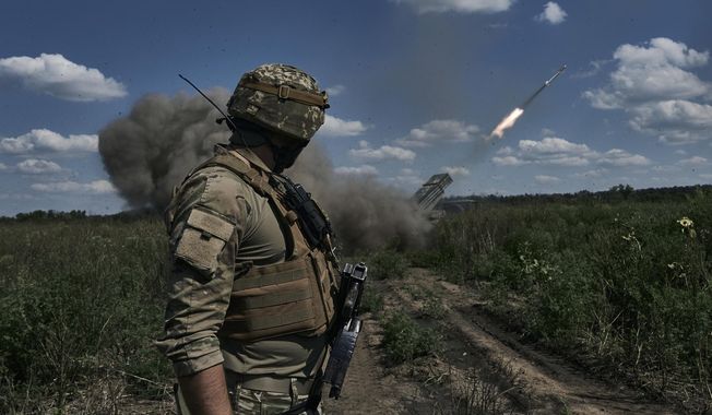 A Ukrainian soldier watches a Grad multiple launch rocket system firing shells with flyers near Bakhmut, Donetsk region, Ukraine, Sunday, Aug. 13, 2023. (AP Photo/Libkos)