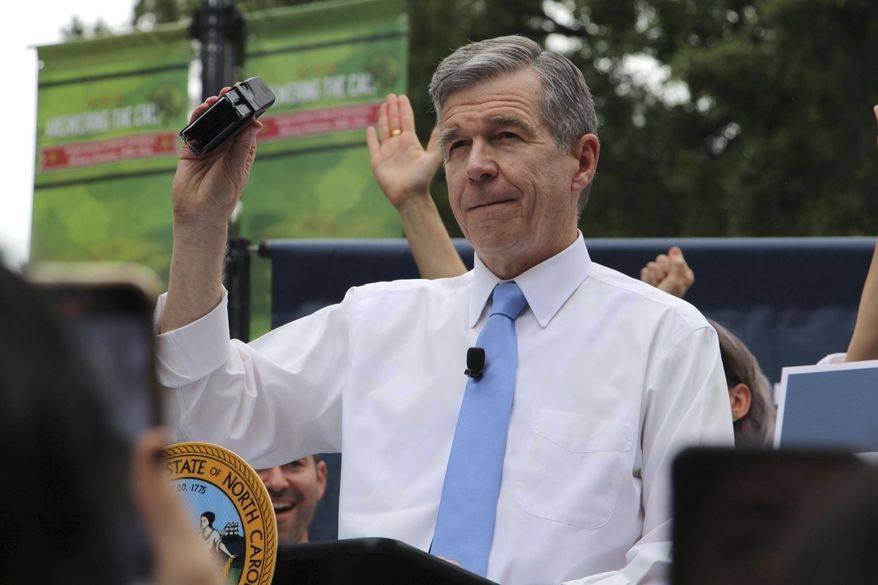 North Carolina Democratic Gov. Roy Cooper affixes his veto stamp to a bill banning nearly all abortions after 12 weeks of pregnancy at a public rally, May 13, 2023, in Raleigh, N.C. Transgender rights take center stage in North Carolina again Wednesday, Aug. 16, as GOP supermajorities in the General Assembly attempt to override the governor's vetoes of legislation banning gender-affirming health care for minors and limiting transgender participation in school sports. (AP Photo/Hannah Schoenbaum, File)