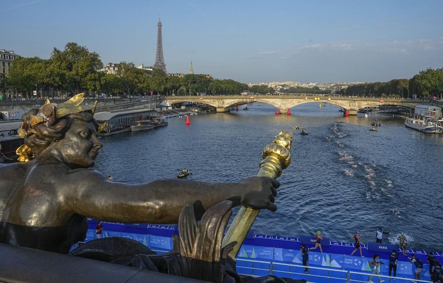 Athletes dive and swim in the Seine river from the Alexander III bridge on the first leg of the women&#x27;s triathlon test event for the Paris 2024 Olympics Games in Paris, Thursday, Aug. 17, 2023. In 2024. The bridge will be the setting for the finish line of the individual cycling time trials, swimming marathon, triathlon and para triathlon. (AP Photo/Michel Euler)