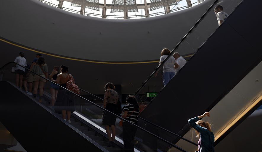 People take the escalator in a shopping mall during a heat wave in Lyon, central France, Wednesday, Aug. 23, 2023. A mall in Southern California will soon require unaccompanied minors to wear identification cards after a crowd of youths started three brawls at the shopping center during last weekend's National Cinema Day promotion. (AP Photo/Laurent Cipriani)
