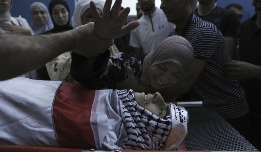 Hiyam Abu Oun mourns her son, Ezzedin Kanan, 20, who succumbed to his wounds sustained during an Israeli army operation last month, during his funeral in the West Bank city of Jenin, Saturday, Aug. 26, 2023. The July 3 raid was the most intense Israeli military operation in years in the West Bank, involving airstrikes and hundreds of ground troops, that left a wide swath of damage in its wake. Kanan's death brings the death toll in the raid to 13. (AP Photo/Nasser Nasser)