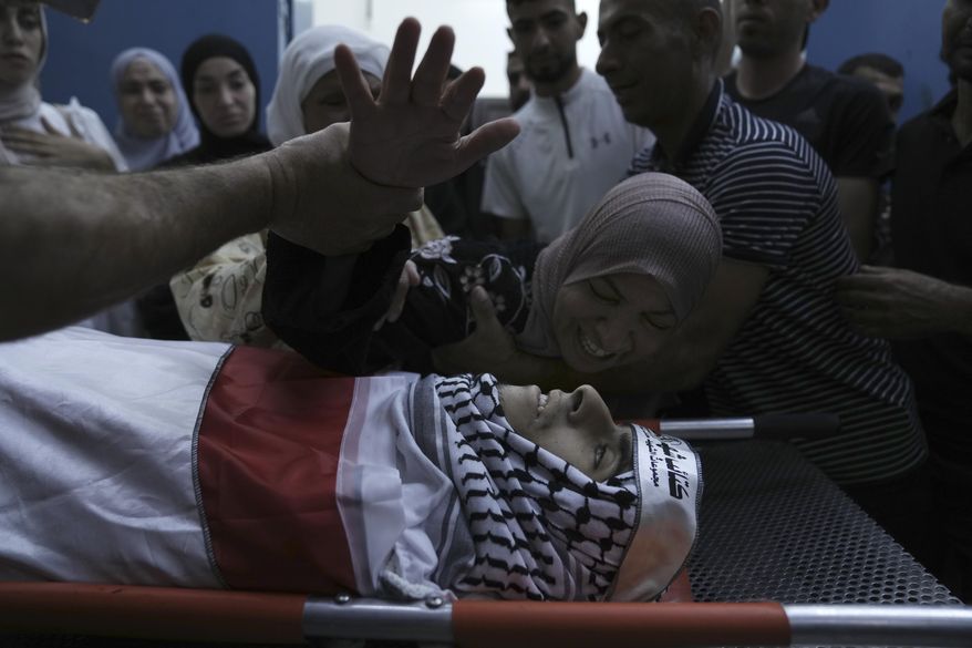 Hiyam Abu Oun mourns her son, Ezzedin Kanan, 20, who succumbed to his wounds sustained during an Israeli army operation last month, during his funeral in the West Bank city of Jenin, Saturday, Aug. 26, 2023. The July 3 raid was the most intense Israeli military operation in years in the West Bank, involving airstrikes and hundreds of ground troops, that left a wide swath of damage in its wake. Kanan's death brings the death toll in the raid to 13. (AP Photo/Nasser Nasser)