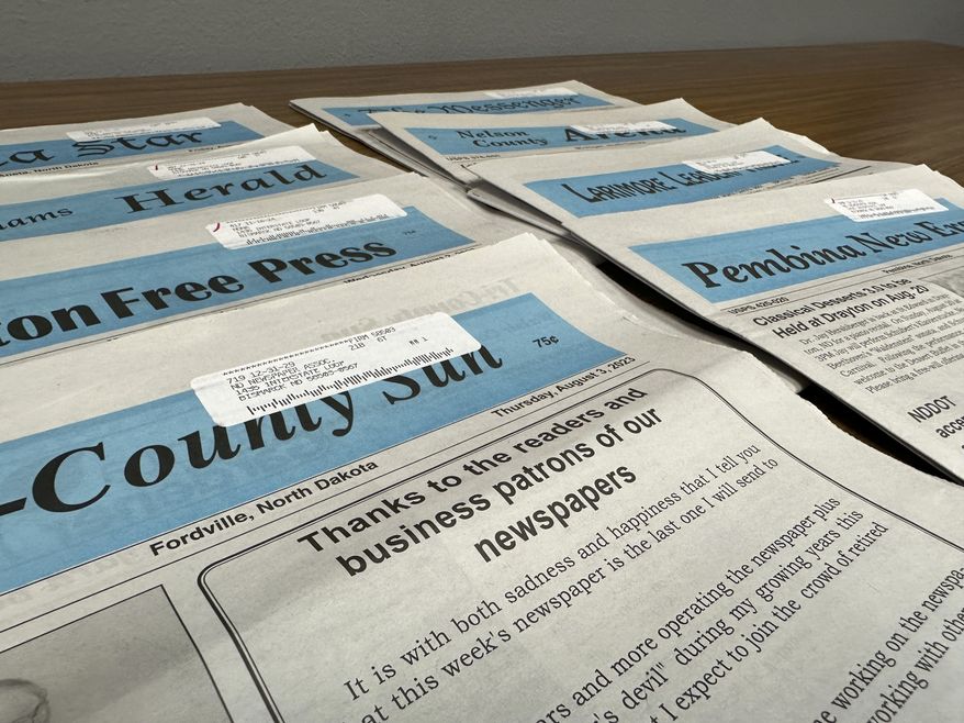 The final editions of eight weekly newspapers rest on a table at the North Dakota Newspaper Association office in Bismarck, N.D., Wednesday, Aug. 16, 2023. Eight weekly newspapers in northeastern North Dakota ceased publication in early August with the closure of the century-old, family-run Ness Press, begun in 1922. The business had no one to take it over, with few businesses and little advertising revenue in its local area. (AP Photo/Jack Dura)