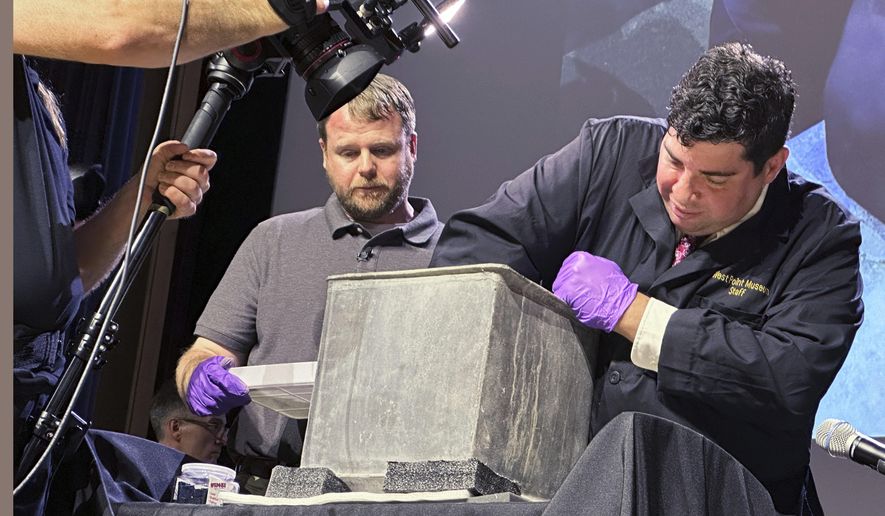 Paul Hudson, left, West Point archeologist, and Michael Diaz, West Point Museum curator, take part in the opening of a lead box believed to have been placed in the base of a monument by cadets almost two centuries ago, at the U.S. Military Academy, Monday, Aug. 28, 2023, in West Point, N.Y. The box contained silt. (AP Photo/Michael Hill)
