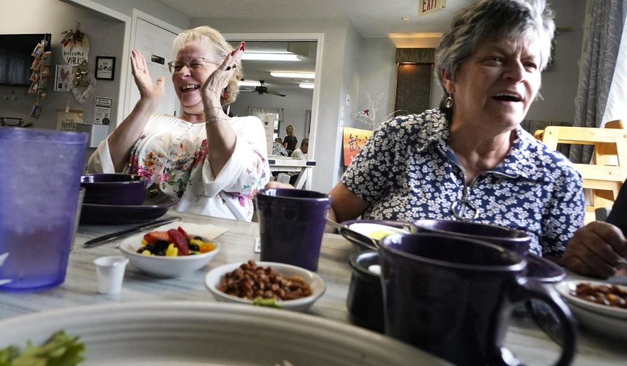 Debbie LaBarre, left, laughs while having breakfast, as part of the Meals on Wheels "Dine Out Club", with her sister, Suzanne Marchand, right, at the White Birch Cafe, Wednesday, Aug. 16, 2023, in Goffstown, N.H. In some states, programs that give struggling restaurants some of the federal and state money set aside to feed seniors have grown in popularity. The restaurants can provide balanced meals with more choices, flexible timing and a judgment-free setting that can help seniors get together to chat and stem loneliness. (AP Photo/Charles Krupa)