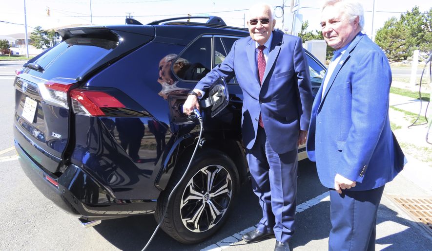 Joseph Fiordaliso, president of the New Jersey Board of Public Utilities, left, and Asbury Park Mayor John Moor, right, speak in front of a new electric vehicle charging station that had not yet been activated in Asbury Park, N.J. on March 21, 2022. Fiordaliso, who was implementing much of New Jersey Gov. Phil Murphy's push for clean energy projects, died on Sept. 6, 2023, at age 78. (AP Photo/Wayne Parry)
