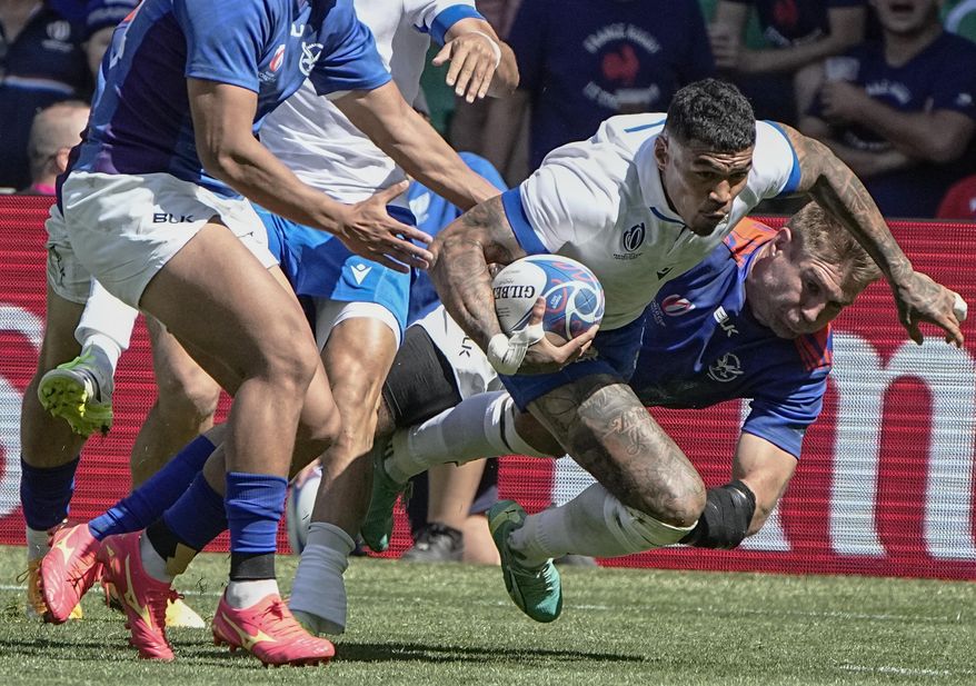 Italy's Montanna Ioane, left, is tackled by Namibia's Tiaan Swanepoel during the Rugby World Cup Pool A match between Italy and Namibia at the Geoffroy Guichard stadium in Saint-Etienne, central France, Saturday, Sept. 9, 2023. (AP Photo/Laurent Cipriani)