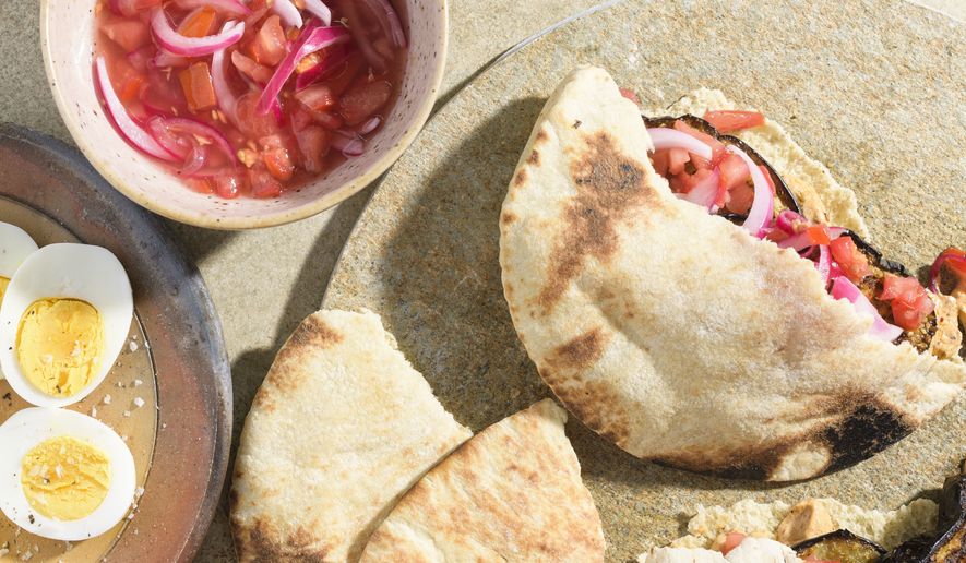 This image released by Milk Street shows a recipe for charred eggplant pita sandwiches with spicy tahini. (Milk Street via AP)