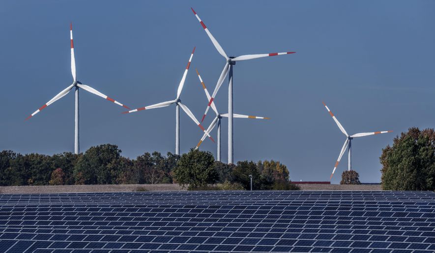 Wind turbines turn behind a solar farm in Rapshagen, Germany, Thursday, Oct. 28, 2021. European Union lawmakers endorsed a deal Tuesday to raise the share of renewables in the bloc’s energy mix, another step to accelerate its green transition away from fossil fuels. The bill, adopted by a large majority — 470 lawmakers voted in favor, 120 against and 40 abstained — foresees an updated renewable energy target of 42.5% of total consumption by 2030. The current goal is 32%. (AP Photo/Michael Sohn, File)