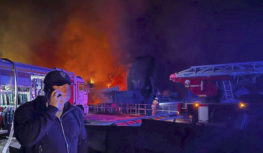 In this handout photo released by the Governor of Sevastopol Mikhail Razvozhaev telegram channel on Wednesday, Sept. 13, 2023, Razvozhaev speaks on the mobile phone as smoke and flame rise from a burning Sevastopol Shipyard in Crimea. The Sevastopol Shipyard in Russian-annexed Crimea is on fire after a Ukrainian attack with 24 people being injured and two ships that were being repaired there sustaining damage. Russia's Defense Ministry said Ukraine launched 10 cruise missiles at the shipyard and three sea drones at Russian ships in the Black Sea. (Sevastopol Governor Mikhail Razvozhaev telegram channel via AP)
