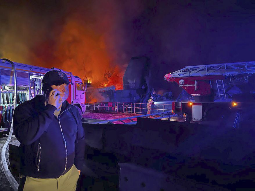 In this handout photo released by the Governor of Sevastopol Mikhail Razvozhaev telegram channel on Wednesday, Sept. 13, 2023, Razvozhaev speaks on the mobile phone as smoke and flame rise from a burning Sevastopol Shipyard in Crimea. The Sevastopol Shipyard in Russian-annexed Crimea is on fire after a Ukrainian attack with 24 people being injured and two ships that were being repaired there sustaining damage. Russia's Defense Ministry said Ukraine launched 10 cruise missiles at the shipyard and three sea drones at Russian ships in the Black Sea. (Sevastopol Governor Mikhail Razvozhaev telegram channel via AP)