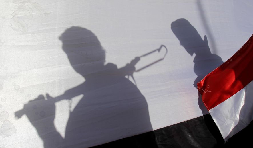 The shadows of Shiite rebels, known as Houthis, are cast on a large representation of the Yemeni flag as they attend a demonstration against an arms embargo imposed by the U.N. Security Council on Houthi leaders, in Sanaa, Yemen, on April 16, 2015. (AP Photo/Hani Mohammed, File)