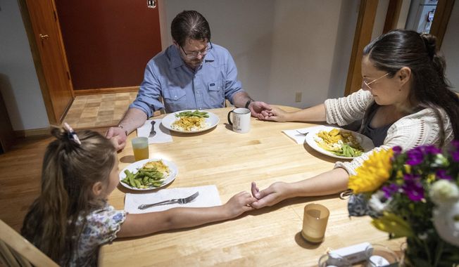 Shane Alderson, his wife, Alisha, and their daughter, Adeline, 5, pray before dinner at their home in Baker City, Ore., on Thursday, Aug. 31, 2023. Shane is Baker County&#x27;s chief commission chair and Alisha is expecting their daughter, Ava, in September. Because of the closing of Baker City&#x27;s only obstetrical unit, the family is traveling to the Boise, Idaho area, a little over 100 miles away, to give birth. (AP Photo/Kyle Green)