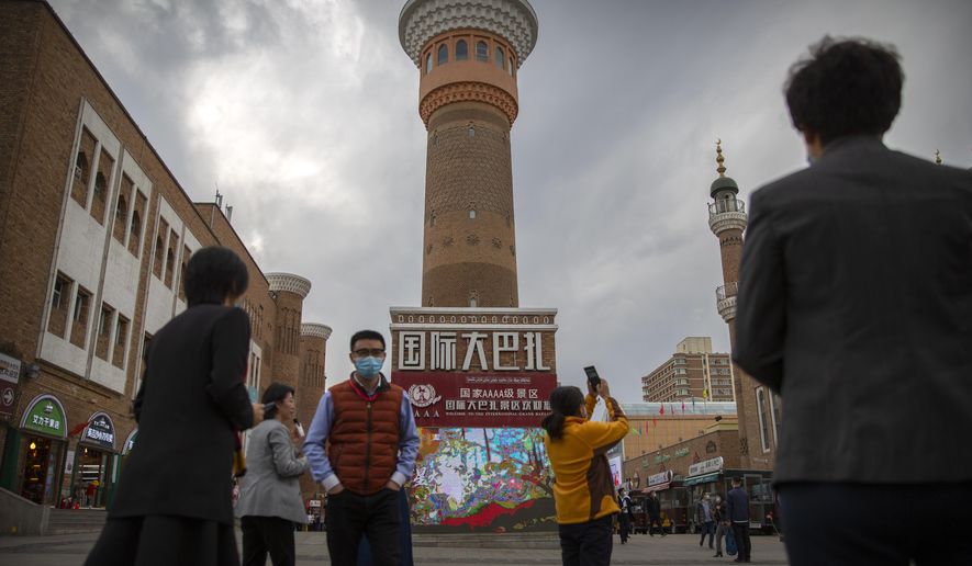 Tourists take photos near a tower at the International Grand Bazaar in Urumqi in western China's Xinjiang Uyghur Autonomous Region, as seen during a government-organized trip for foreign journalists on April 21, 2021. A prominent Uyghur scholar specializing in the study of her people's folklore and traditions has been sentenced to life in prison, according to a U.S.-based foundation that works on human rights cases in China. Rahile Dawut was convicted on charges of endangering state security in December 2018 in a secret trial, the San Francisco-based Dui Hua Foundation said in a statement Thursday, Sept. 21, 2023. (AP Photo/Mark Schiefelbein)