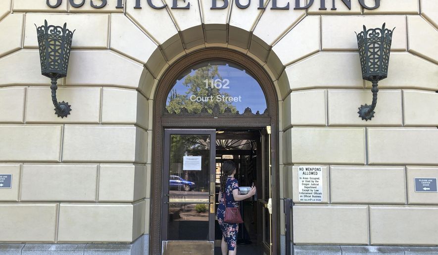 A woman enters the Oregon Department of Justice building in Salem, Ore., May 28, 2020. According to a ballot measure passed by Oregon voters, state senators who accumulated 10 or more unexcused absences at the Legislature during a record-setting Republican walkout are supposed to be disqualified from running for re-election, but several filed suit in the Oregon Court of Appeals, challenging the measure. On Monday, Sept. 25, 2023, the appeals court formally asked the state Supreme Court to handle the case. (AP Photo/Andrew Selsky, File)