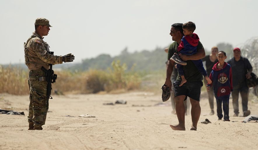 Migrants who crossed the Rio Grande river to the U.S. from Mexico seek direction from a guardsman, Friday, Sept. 22, 2023, in Eagle Pass, Texas. (AP Photo/Eric Gay)