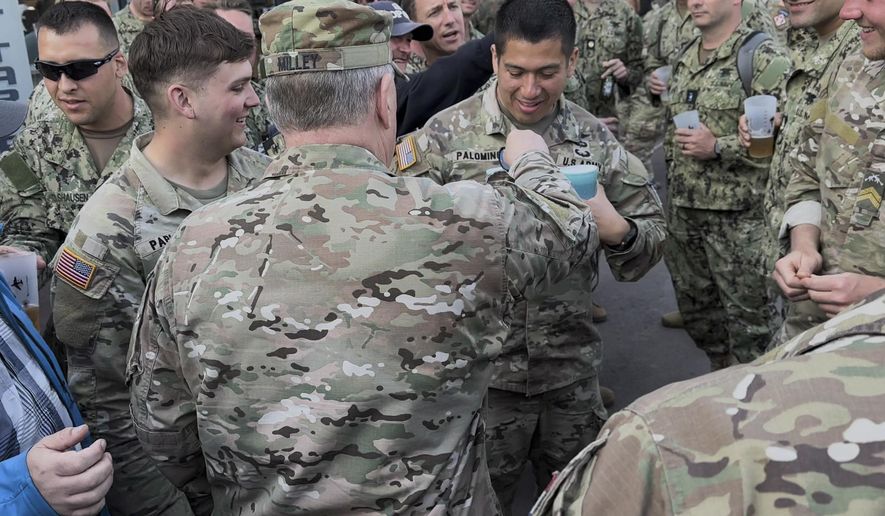 Joint Chiefs Chairman Gen. Mark Milley drops his chairman's coin into Capt. Palomino's beer as he walks through crowds of soldiers celebrating the anniversary of D-Day in the town square of Sainte-Mere-Eglise in Normandy, France on June 4, 2023. This was Milley's last visit to Normandy as a soldier, just a few months before he was to retire, and he soaked it in talking to soldiers and veterans, and handing out his chairman's coin to many of them. (AP Photo/Tara Copp)