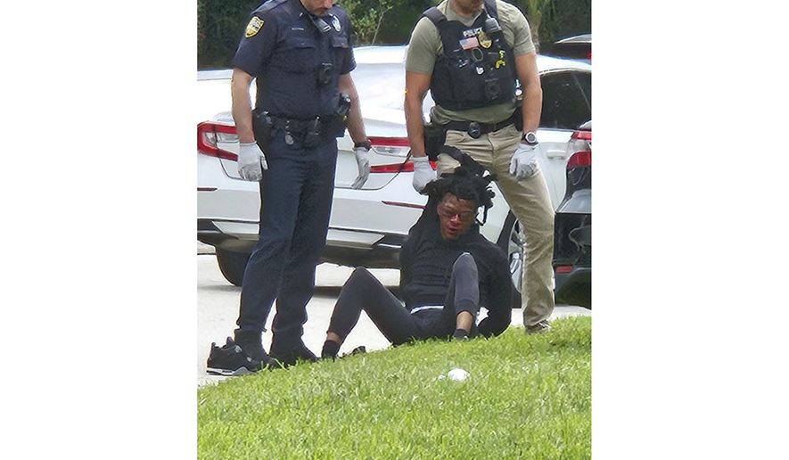 This photo taken from cellphone video provided by Ruby Anderson shows Le’Keian Woods, with swollen eyes and a bloody face sitting on the ground surrounded by officers, as he's taken into custody, Friday, Sept. 29, 2023, in northeast Florida. The Jacksonville Sheriff’s Office was conducting an administrative review of what happened to see if any policies were violated, the agency said in a statement. (Ruby Anderson via AP)